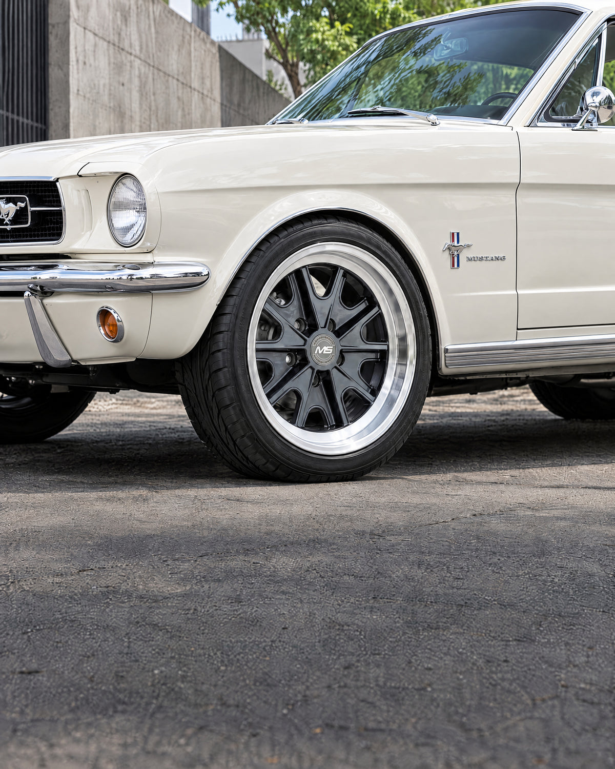 Mustang clásico blanco con rines grafito de ocho radios y labio pulido.